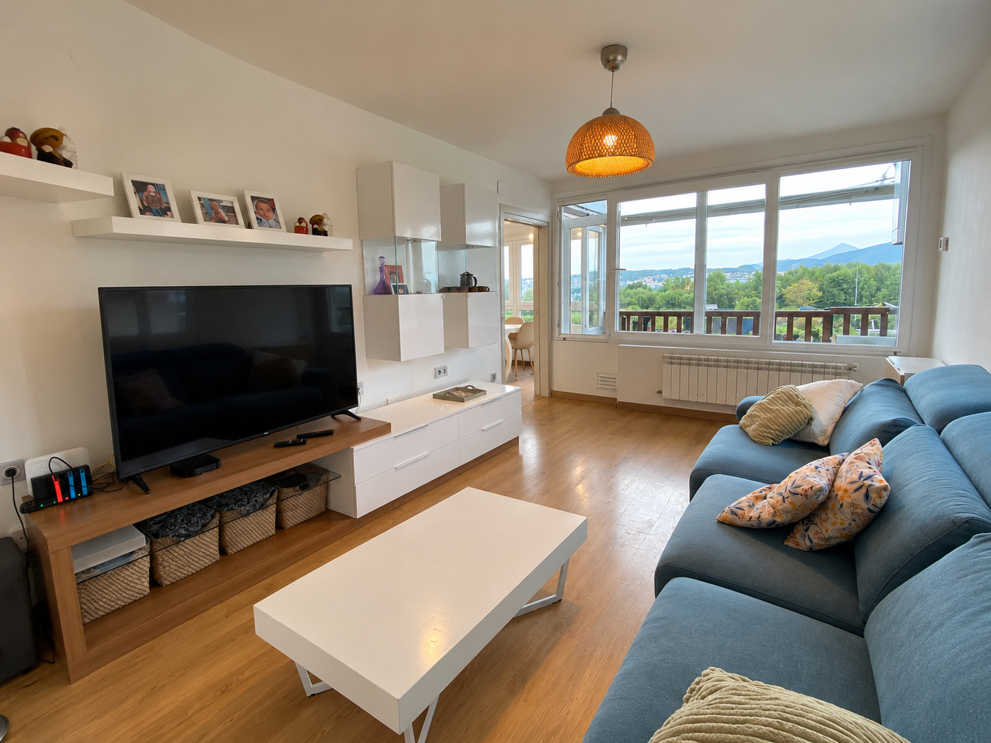 Salón con sofá azul, televisor y vistas a la montaña